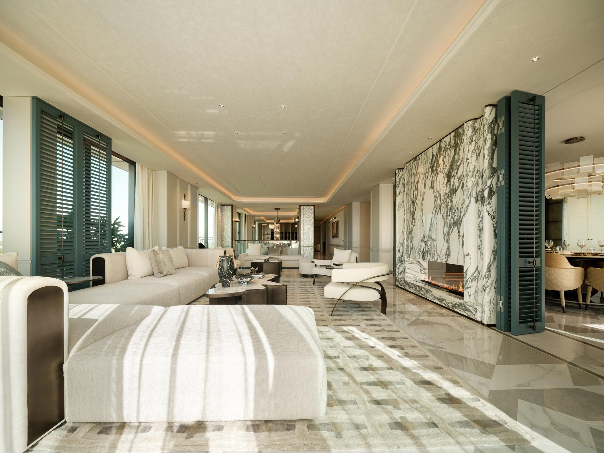 Luxurious, spacious living room with elegant marble accents, sleek furniture, and a modern fireplace. Soft natural light creates a serene atmosphere.