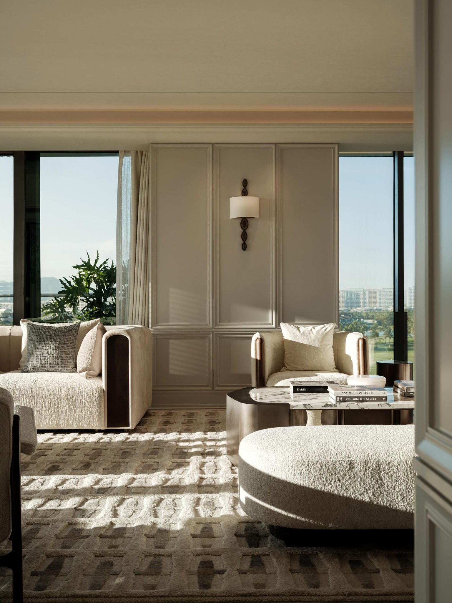 Luxurious living room with elegant beige furniture, soft lighting, and large windows offering a scenic city view. Warm, inviting atmosphere.