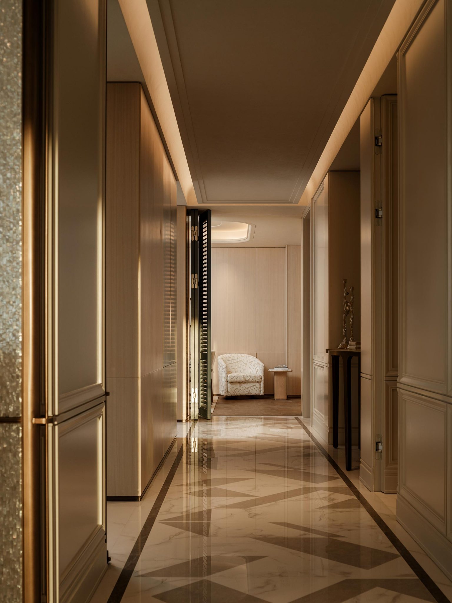 Elegant hallway with polished marble flooring leads to a cozy, softly lit sitting area featuring a plush armchair and small table, conveying warmth.