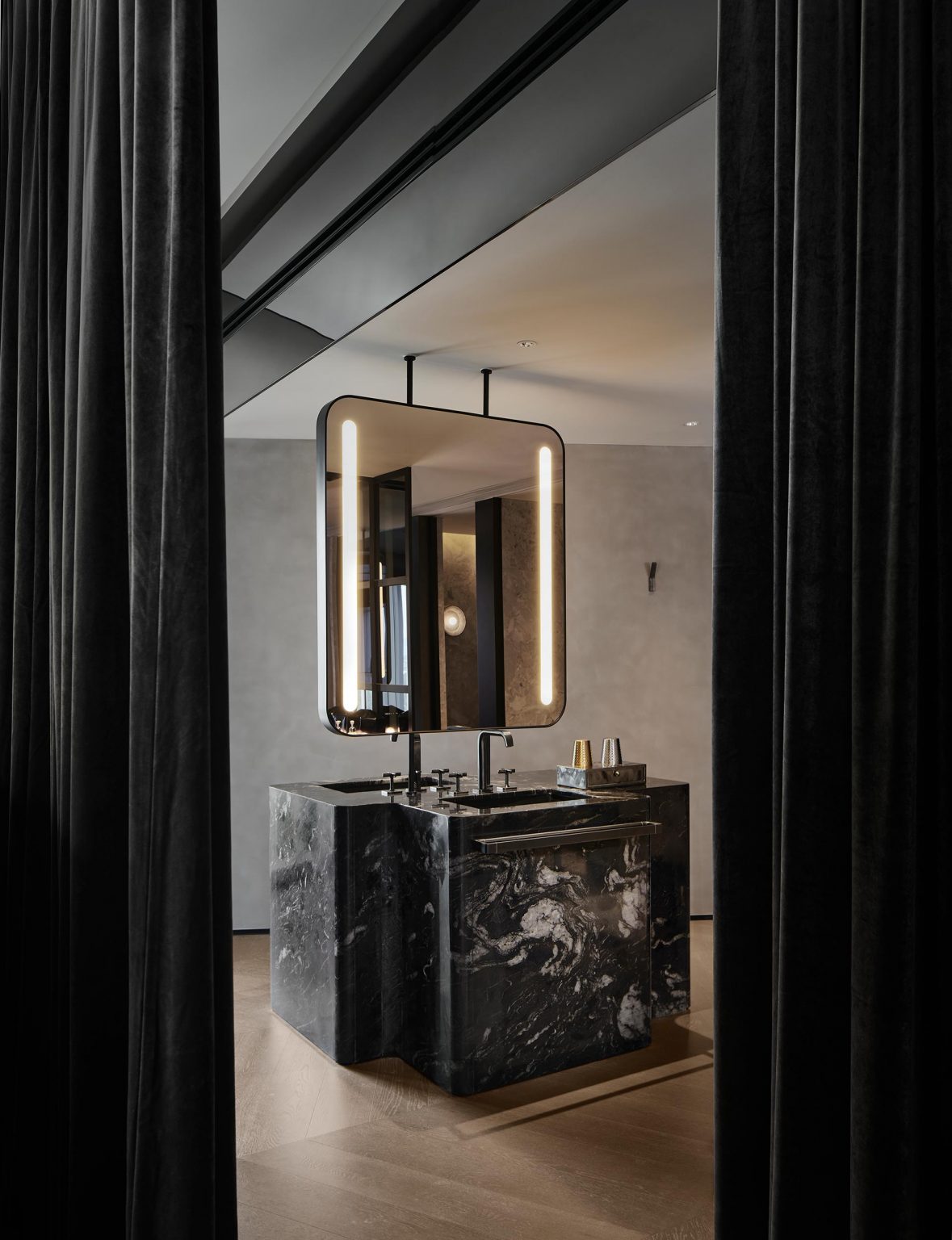 Modern bathroom with a sleek black marble vanity and illuminated mirror. Minimalist decor, dark tones, and soft lighting create a luxurious ambiance.