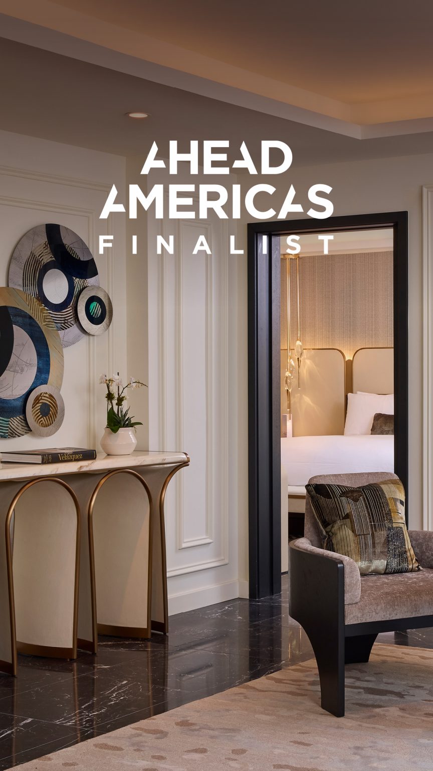 Elegant hotel interior showcasing a stylish suite entry with modern art, plush chair, decorative console table, and soft lighting. Text reads “Ahead Americas Finalist.”