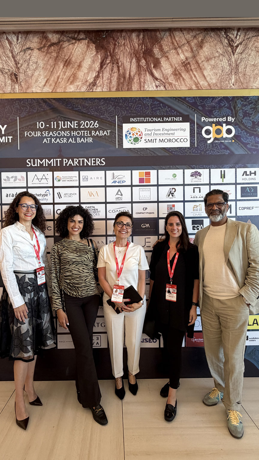 Five people posing and smiling in front of Hospitality Innovation Summit backdrop with logos. They're wearing conference badges, conveying a professional and friendly atmosphere.